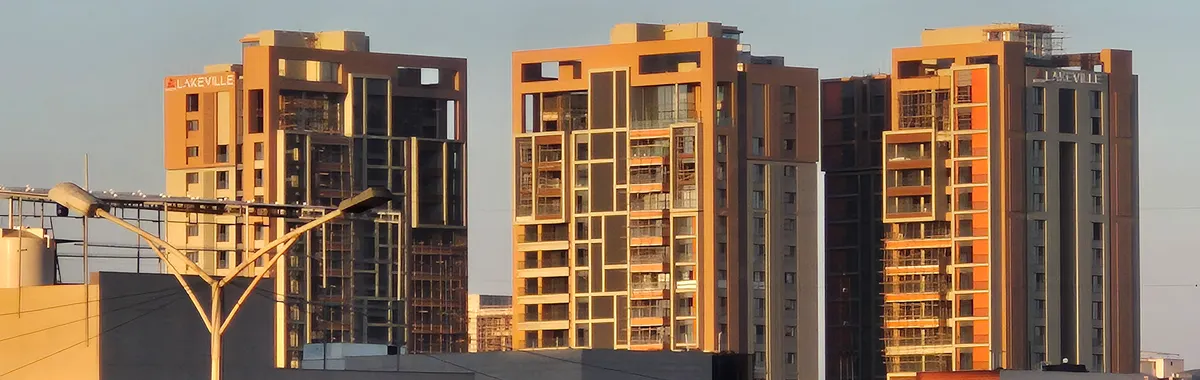 Contemporary high-rise buildings in Surat, India, captured at sunset with clear skies.