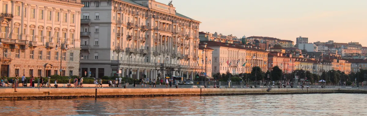 Beautiful sunset over historic waterfront buildings in Trieste, Italy reflecting off the Adriatic Sea.