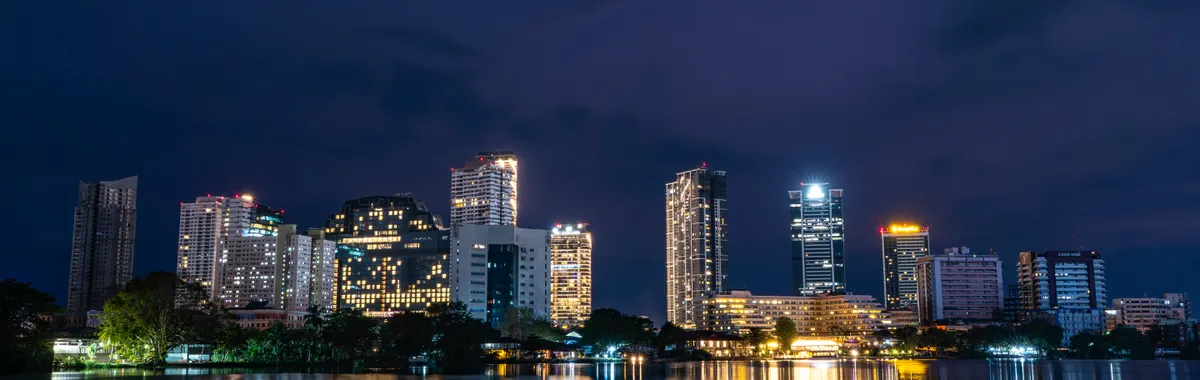 Stunning night view of Colombo skyline reflecting in serene water. Captivating city lights create a vibrant atmosphere.