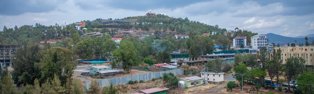 אתיופיה: Captivating aerial view of Gondar, Ethiopia with lush greenery and architecture under a cloudy sky.