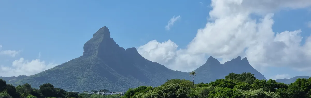 מאוריציוס: Capture of Mauritius' iconic mountains and lagoon under clear blue sky.