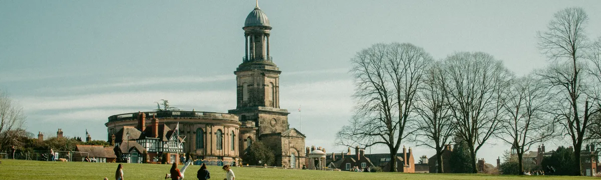 צ׳אד: A sunny view of St Chad's Church and people relaxing in The Quarry, Shrewsbury.