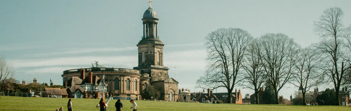 צ׳אד: A sunny view of St Chad's Church and people relaxing in The Quarry, Shrewsbury.