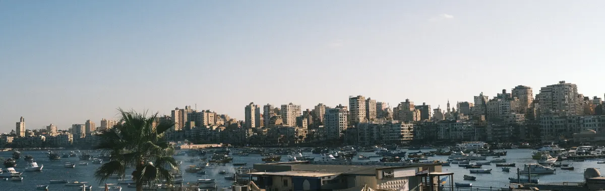 Captivating skyline of Alexandria with boats and historic fortifications against a clear sky.