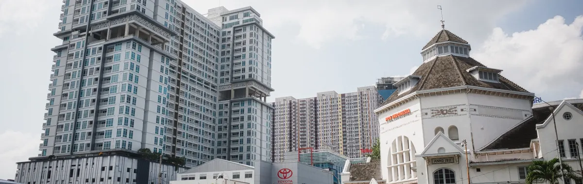 High-rise towers stand next to a historic building in Medan, Indonesia, showcasing architectural diversity.