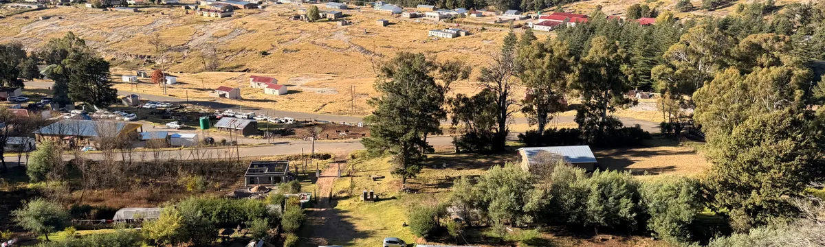 לסוטו: A picturesque aerial view of a rural village in Lesotho, surrounded by mountains and lush greenery.
