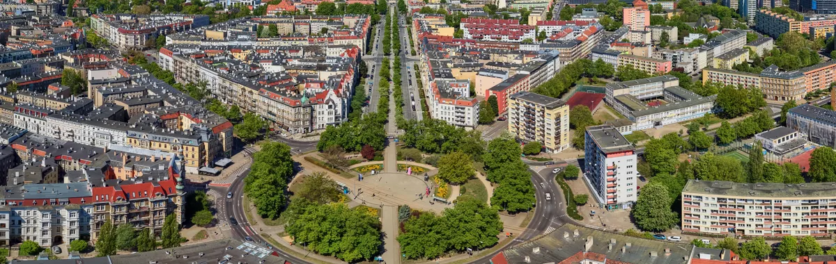 A stunning aerial view of Szczecin, showcasing its urban structure, residential buildings, and greenery on a sunny day.