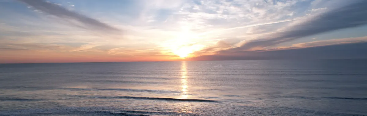 Beautiful sunrise over Virginia Beach with gentle waves and vibrant skies, perfect for relaxation themes.