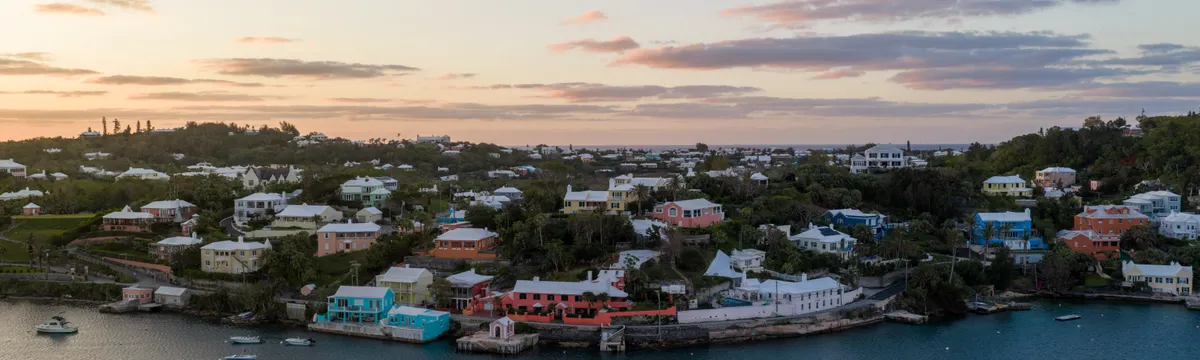 ברמודה: Aerial view of Bermuda's coastline at sunrise showcasing vibrant houses and calm waters.