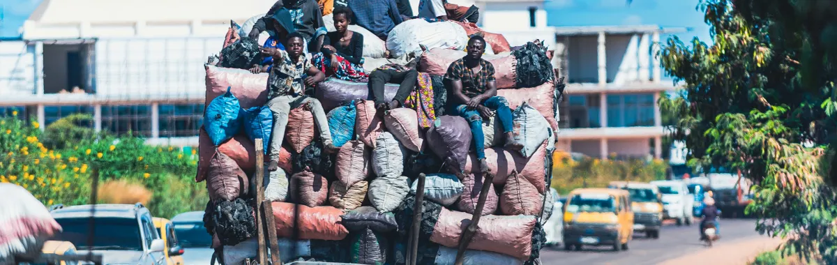 A heavily loaded truck with people and goods navigating a busy street in Lubumbashi, showcasing urban mobility challenges.