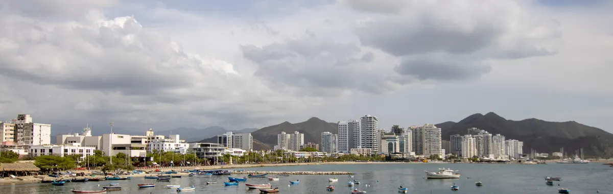 Skyline of Santa Marta, Colombia, with boats in the foreground and mountains in the background.