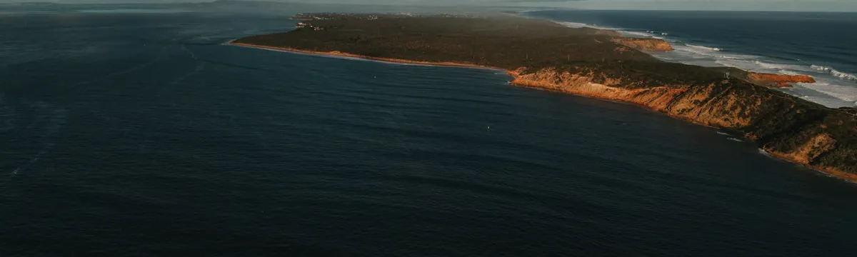 אוסטרליה: A breathtaking aerial view of the rugged coastline of Portsea, Victoria, Australia, bathed in sunlight.