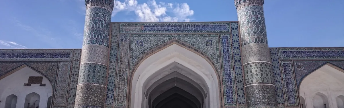 Impressive façade of the Great Mosque in Herat, Afghanistan, showcasing intricate Islamic architecture and blue sky backdrop.