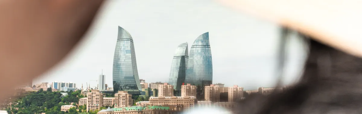 A scenic view of Baku's iconic Flame Towers seen through the perspective of a person adjusting a sunhat.
