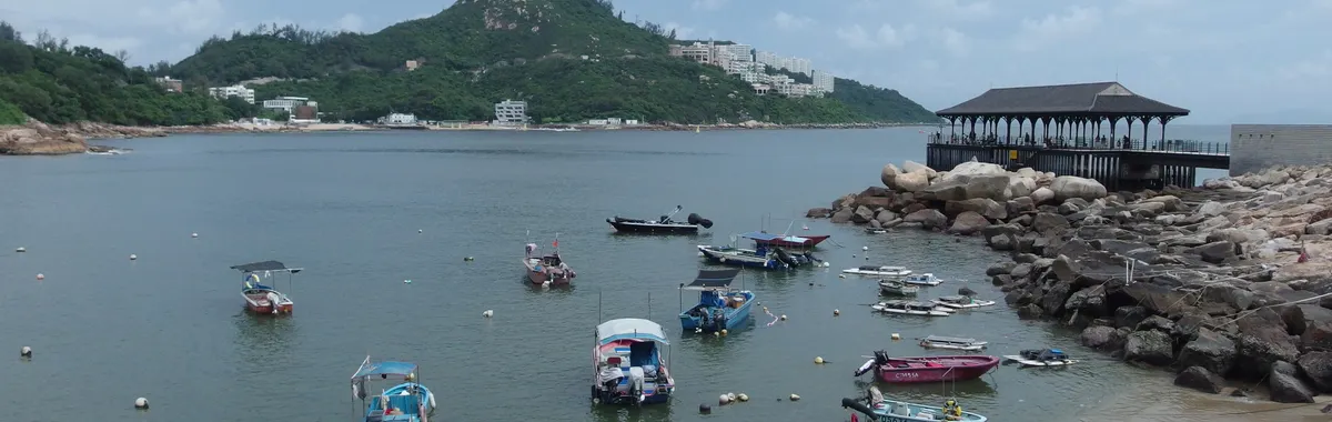 Tranquil scene of fishing boats at Stanley Bay, Hong Kong, beside Blake Pier on a cloudy day.
