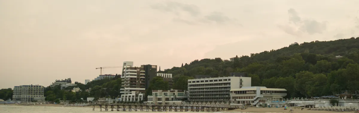 Scenic view of Varna's coastline with beachfront buildings during sunset, showcasing a tranquil summer evening.