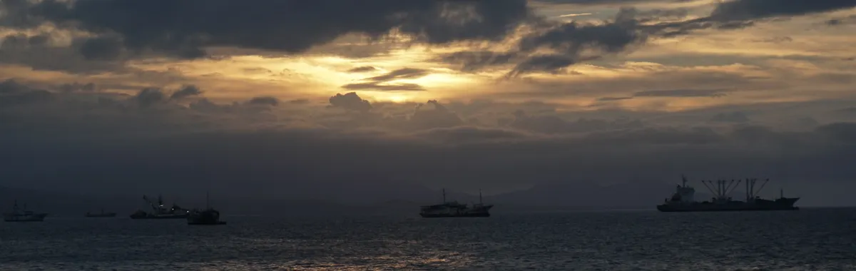איי שלמה: Serene sunset with ships silhouetted against the cloudy sky over Solomon Islands.