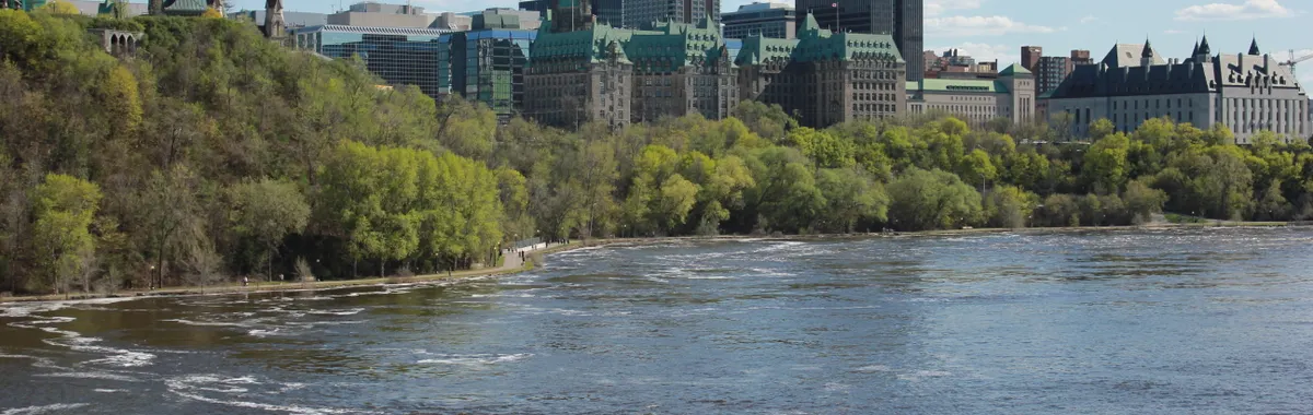 A scenic view of Ottawa's Parliament buildings and the Ottawa River on a clear day.