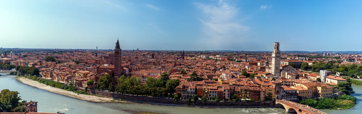 Stunning aerial view of Verona cityscape, featuring the Adige River winding through historic architecture under a clear blue sky.