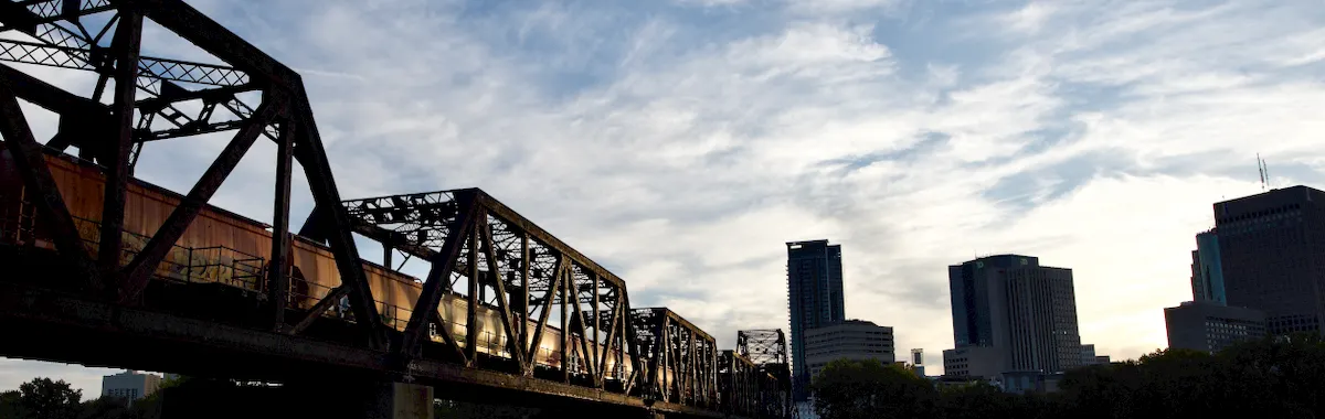 A striking view of the train bridge and skyline over the Assiniboine River in Winnipeg, Canada.