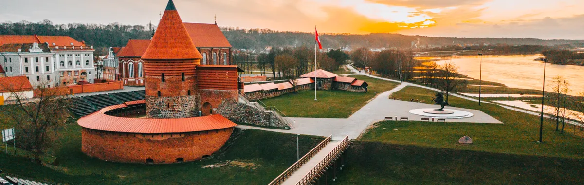Stunning aerial view of historic Kaunas Castle in Lithuania during golden hour, showcasing vibrant skyline.