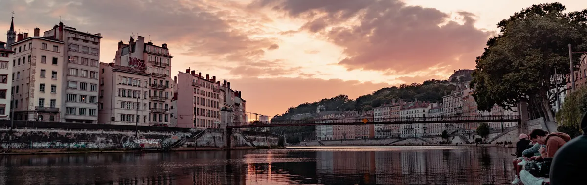 Beautiful sunset view over the Saone River in Lyon, France, showcasing urban townhouses and reflections.