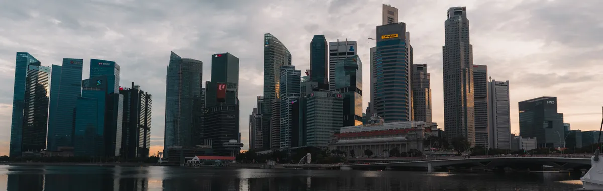 Dramatic skyline of Singapore reflecting on waterfront at dusk with towering skyscrapers.
