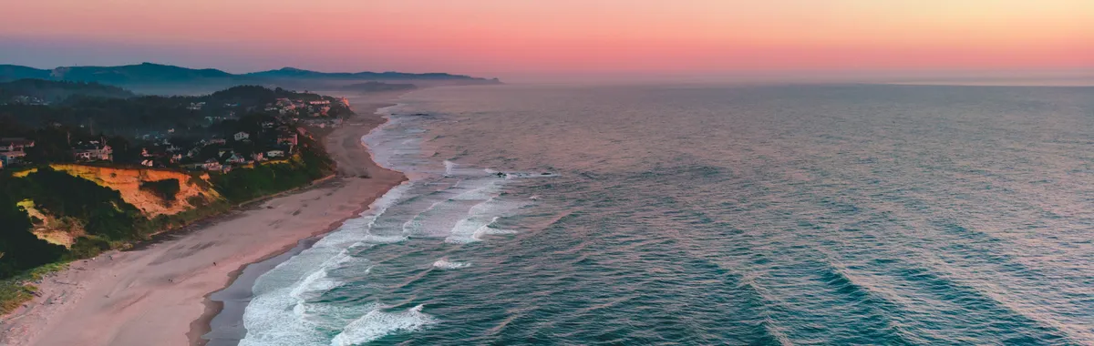 A breathtaking aerial view of Lincoln City's coastline during a vibrant sunset.