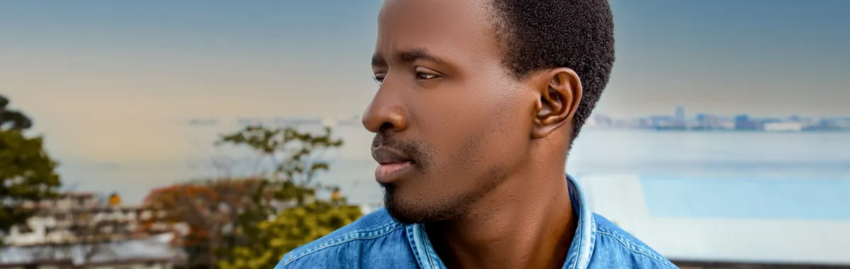 Side profile of a man outdoors in Brazzaville, showcasing serene expression against an urban backdrop.
