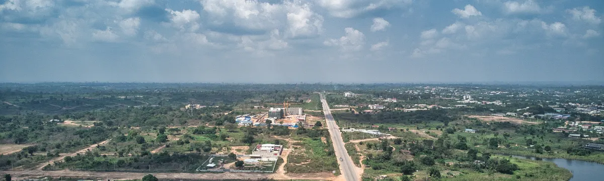 חוף השנהב: Aerial view of Yamoussoukro, Côte d'Ivoire, showcasing suburban landscapes, roads, and a lake.