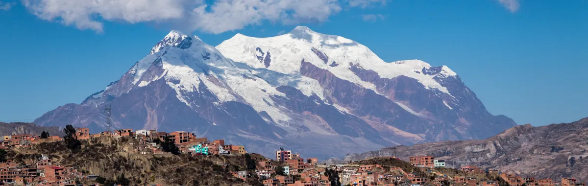 Panoramic view of snow-capped Illimani Mountain towering over the vibrant cityscape of La Paz, Bolivia.