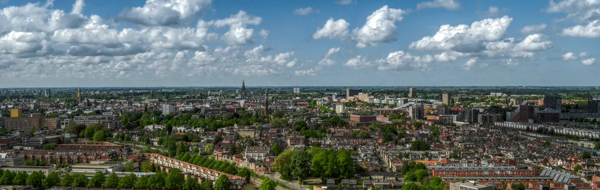 Aerial view of Groningen city skyline with a cloudy sky, showcasing urban architecture and green spaces.