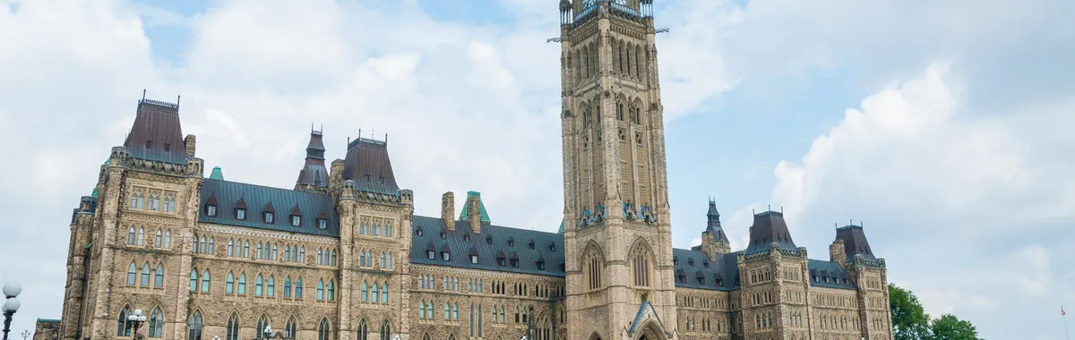 קנדה: Stunning photo of Canada's Parliament Hill in Ottawa under a clear sky, showcasing Gothic Revival architecture.