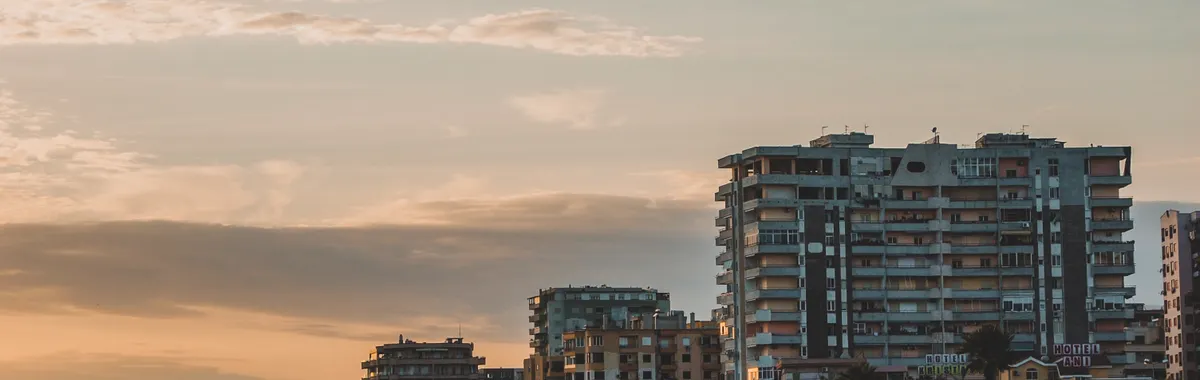 Scenic view of Durrës coastline at sunset featuring modern buildings and a vibrant promenade.