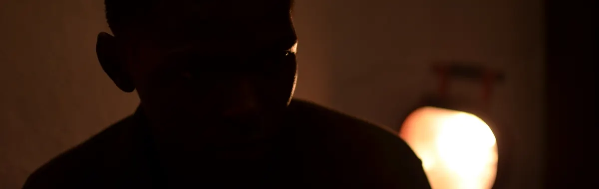 A mysterious silhouette of an adult in warm, dim indoor lighting in Bamako, Mali.