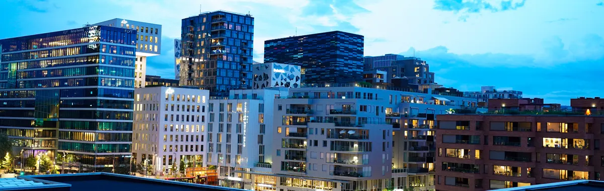 Illuminated modern buildings in Oslo's downtown at twilight, showcasing architecture.