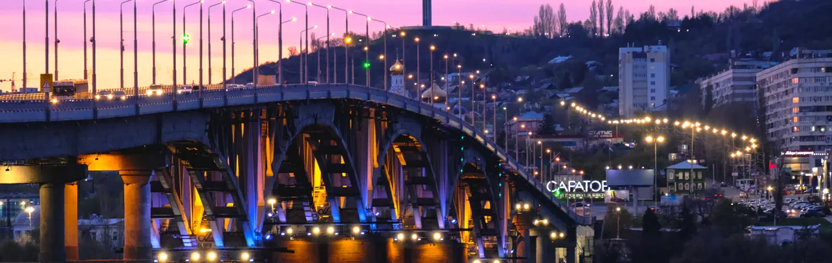 Stunning twilight view of a bridge in Saratov, Russia, with vibrant street lights and city skyline.