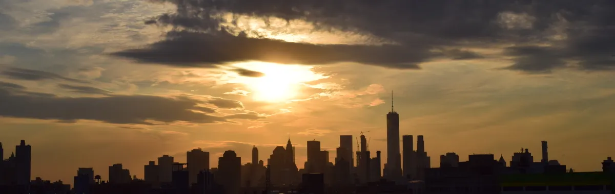 Silhouette of the New York City skyline against a vibrant sunset sky.