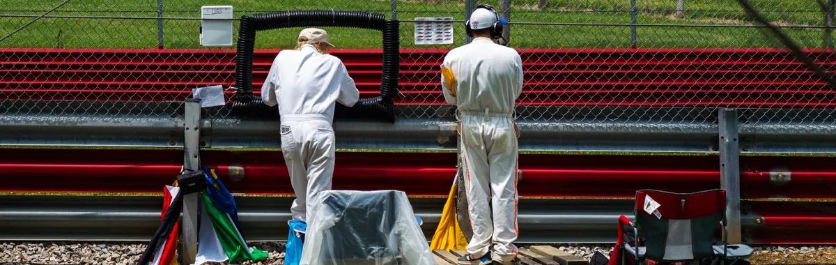 Race officials in coveralls at a Lexington, OH track, managing flags and equipment