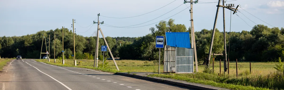 Scenic rural road in Sinitsyna, Tyumen with utility poles, fields, and clear blue sky.