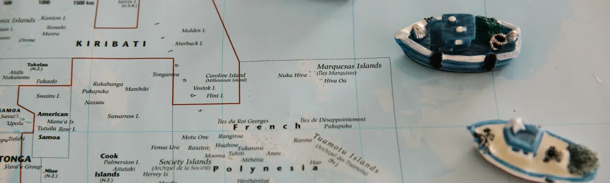 קיריבאטי: Miniature toy ships placed on a map of the South Pacific Ocean, featuring Kiribati.
