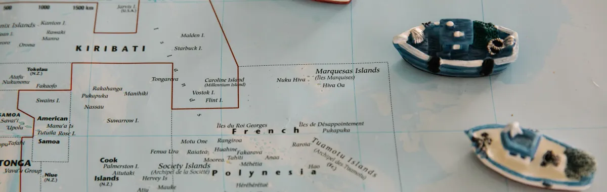 קיריבאטי: Miniature toy ships placed on a map of the South Pacific Ocean, featuring Kiribati.