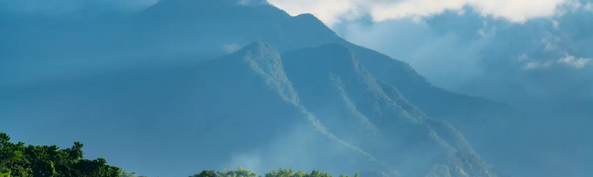 ג׳מייקה: Serene view of the Blue Mountains in Jamaica, shrouded in clouds and sunlight.