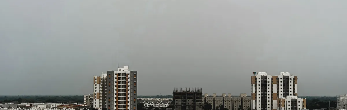 A view of urban residential and commercial buildings under an overcast sky in Vadodara, India.