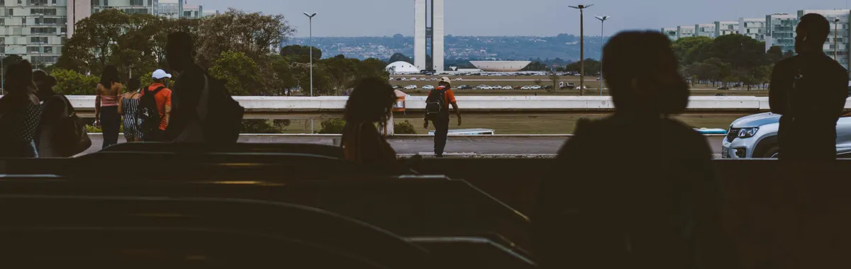 Silhouettes of people in an underpass with Brasília's National Congress in the background.